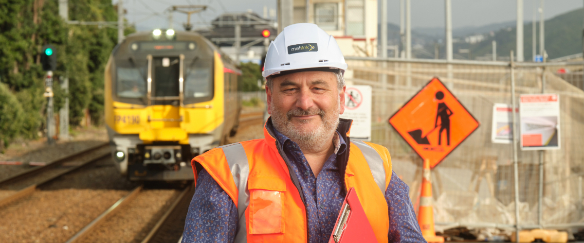 Man wearing hi vis standing in front of wellington railway station train tracks